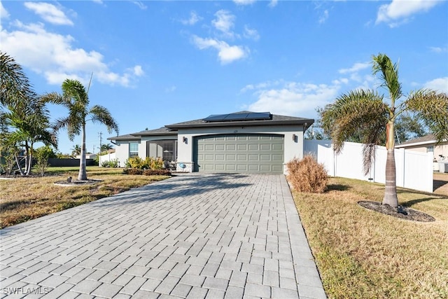 view of front of home with a garage, a front yard, and solar panels