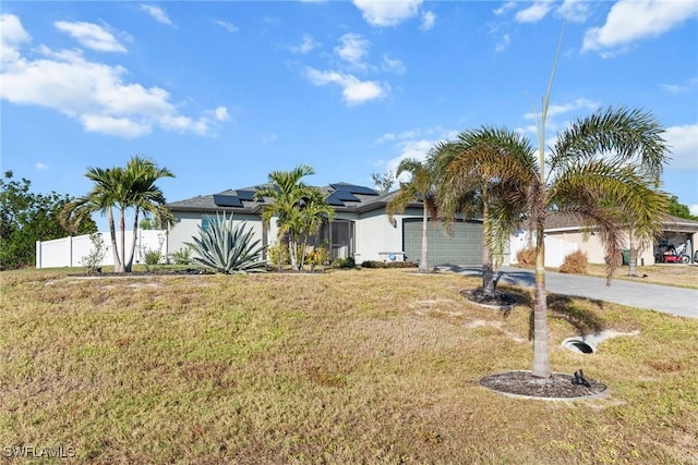 view of front of property featuring solar panels, a garage, and a front lawn