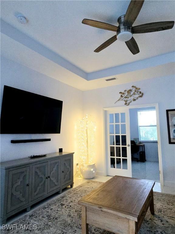 living room featuring ceiling fan, a raised ceiling, and visible vents