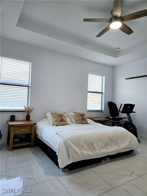 bedroom featuring a raised ceiling and ceiling fan