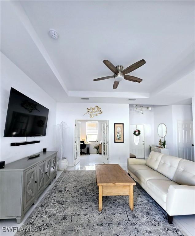 living room featuring ceiling fan, french doors, and a tray ceiling