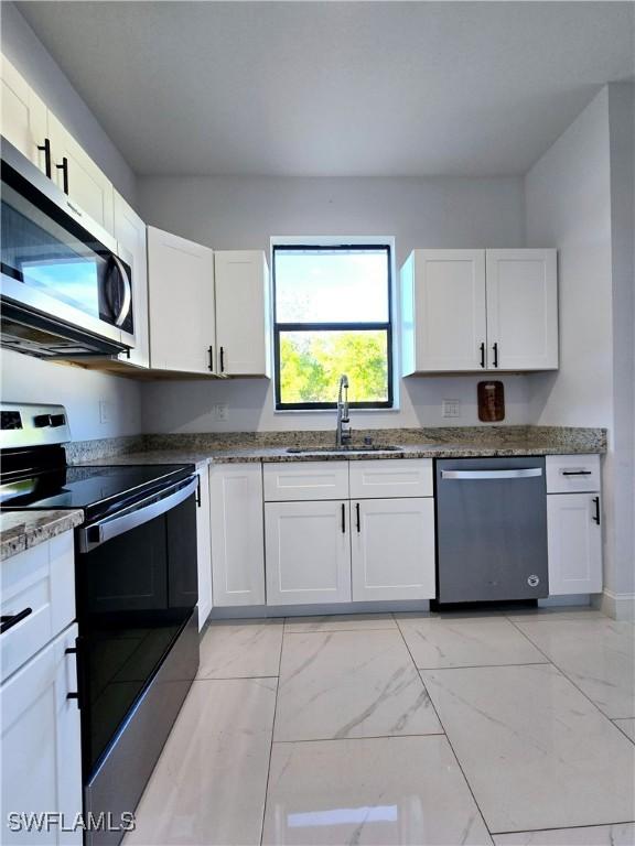 kitchen with sink, white cabinets, dark stone counters, and appliances with stainless steel finishes