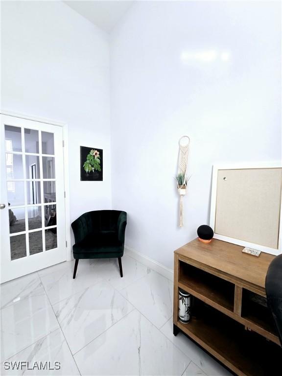 sitting room with marble finish floor, a high ceiling, baseboards, and french doors