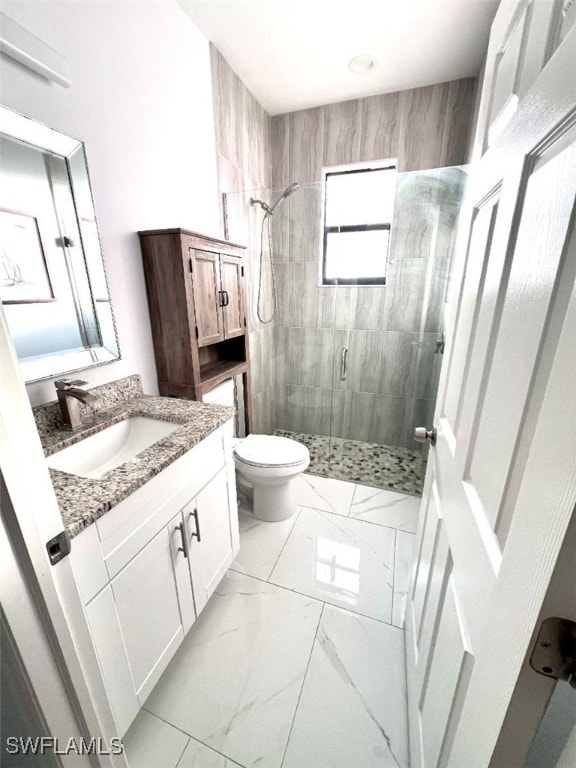 full bath with toilet, marble finish floor, vanity, and a stall shower