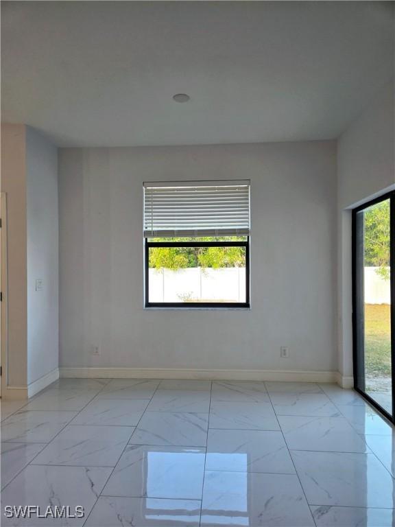 spare room with marble finish floor and baseboards