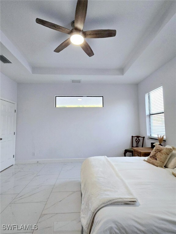 bedroom with ceiling fan and a tray ceiling