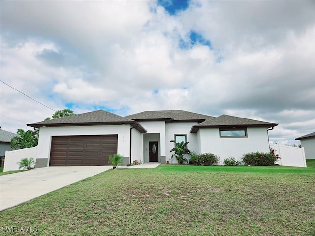 prairie-style home featuring a front yard, fence, driveway, and an attached garage