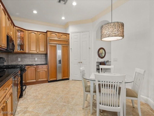 kitchen featuring tasteful backsplash, dark stone counters, crown molding, black appliances, and decorative light fixtures