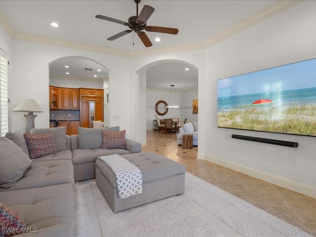 tiled living room with ceiling fan and crown molding