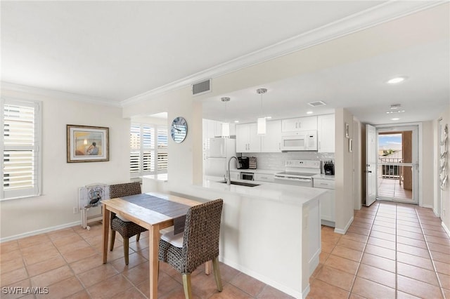 kitchen with kitchen peninsula, white cabinetry, decorative light fixtures, and white appliances