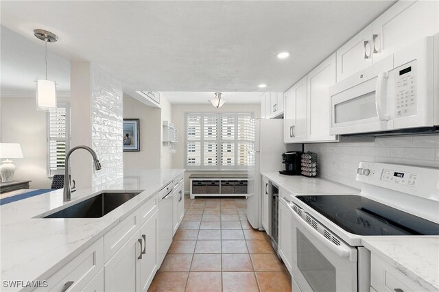 kitchen with white cabinetry, sink, backsplash, pendant lighting, and white appliances