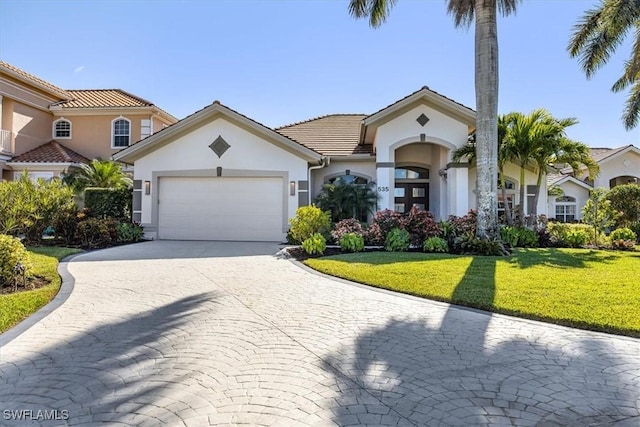 mediterranean / spanish home featuring a garage and a front lawn