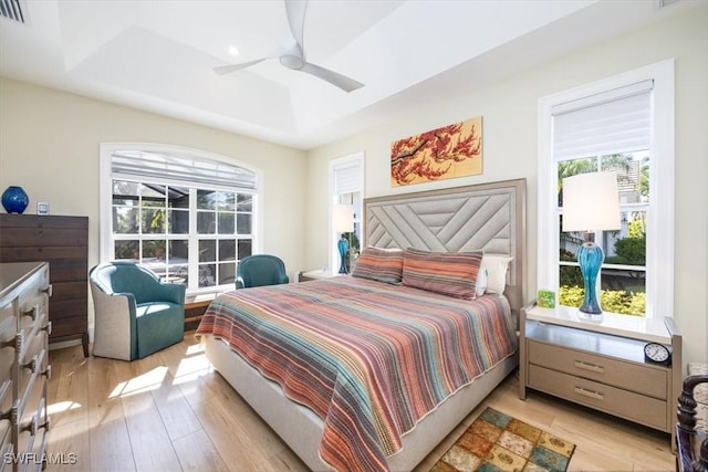 bedroom with ceiling fan, light hardwood / wood-style flooring, and multiple windows