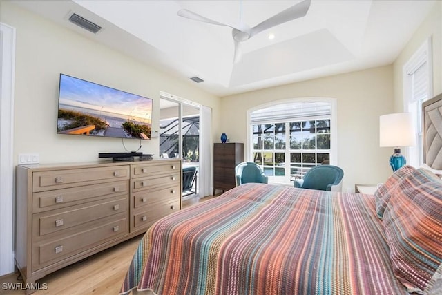 bedroom featuring ceiling fan, light hardwood / wood-style floors, and a raised ceiling