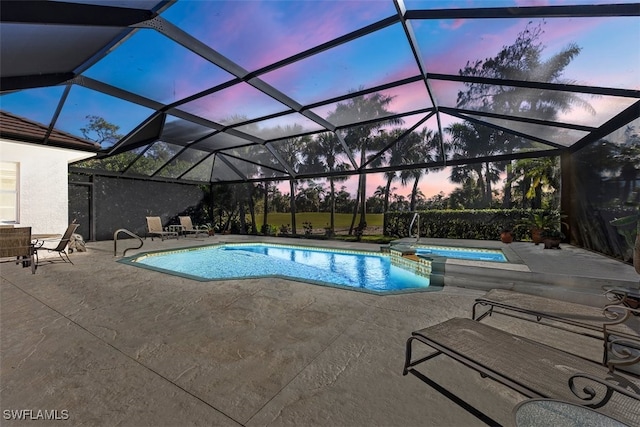 pool at dusk with glass enclosure, an in ground hot tub, and a patio