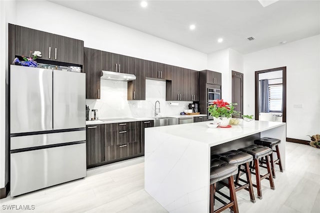 kitchen featuring a breakfast bar, backsplash, sink, a kitchen island, and stainless steel appliances