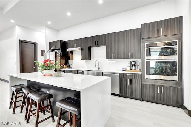 kitchen featuring a kitchen breakfast bar, a center island, sink, and appliances with stainless steel finishes