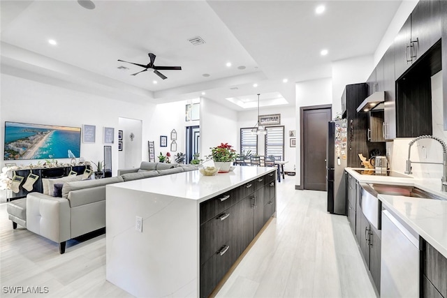 kitchen with sink, a center island, stainless steel appliances, light hardwood / wood-style flooring, and pendant lighting