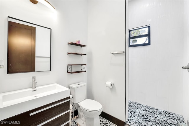 bathroom featuring a tile shower, tile patterned floors, vanity, and toilet