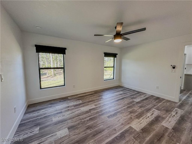 spare room with dark hardwood / wood-style flooring, a wealth of natural light, and ceiling fan