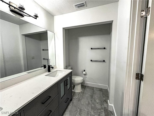 bathroom with tile patterned floors, vanity, toilet, and a textured ceiling