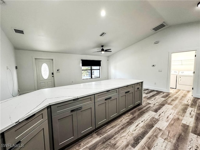 kitchen featuring dark hardwood / wood-style flooring, gray cabinetry, ceiling fan, separate washer and dryer, and lofted ceiling