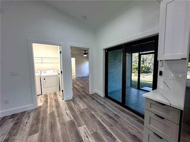 interior space with washing machine and clothes dryer, ceiling fan, high vaulted ceiling, and light hardwood / wood-style floors