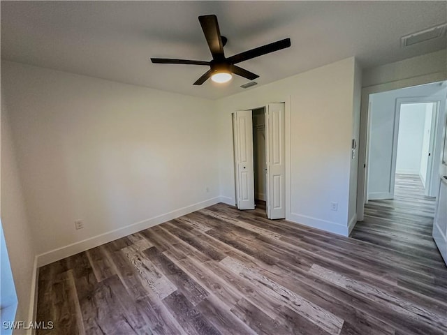 unfurnished bedroom with a closet, ceiling fan, and dark wood-type flooring