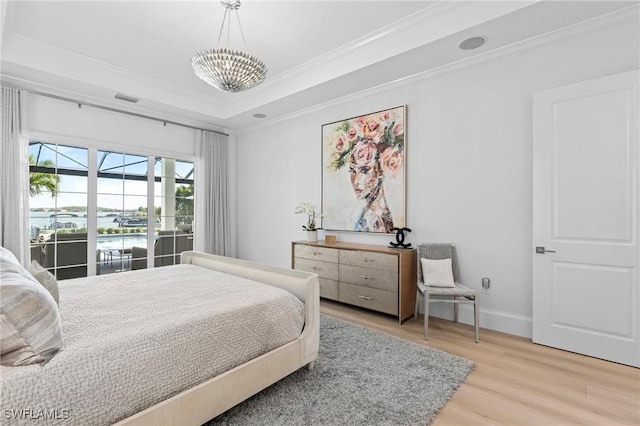 bedroom with a raised ceiling, crown molding, a water view, a chandelier, and light hardwood / wood-style floors