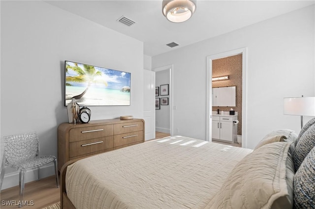 bedroom with ensuite bathroom and light hardwood / wood-style flooring