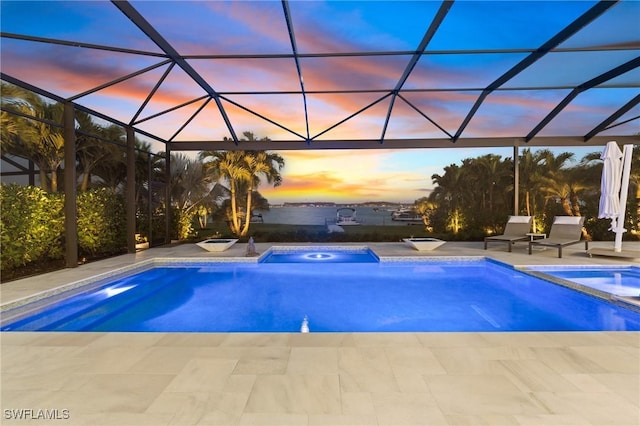 pool at dusk featuring a patio area and a lanai