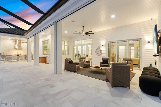 patio terrace at dusk with outdoor lounge area, ceiling fan, and a lanai