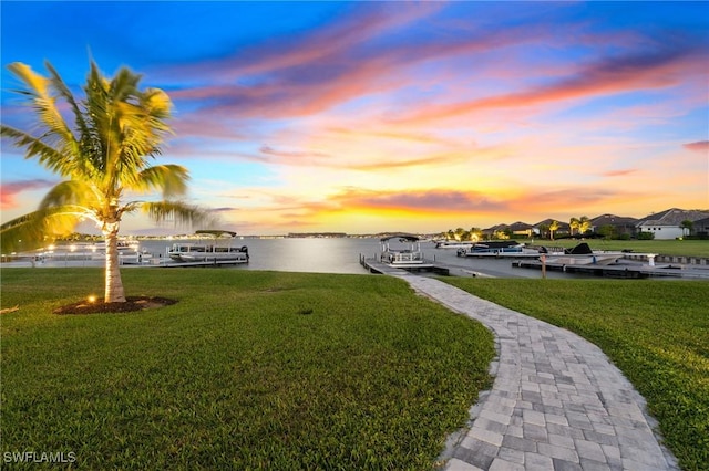 exterior space with a boat dock, a water view, and a yard