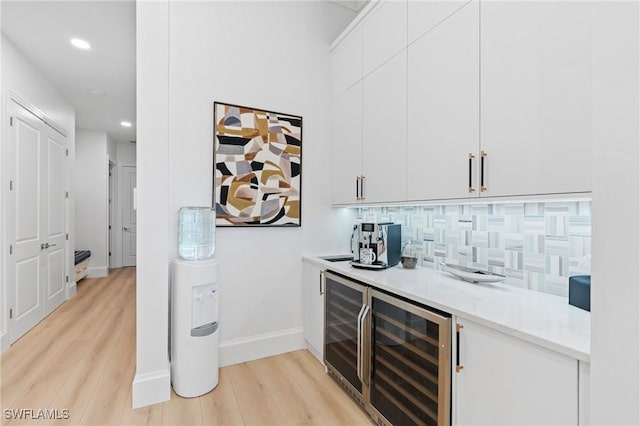 bar featuring light hardwood / wood-style floors, white cabinetry, backsplash, and beverage cooler