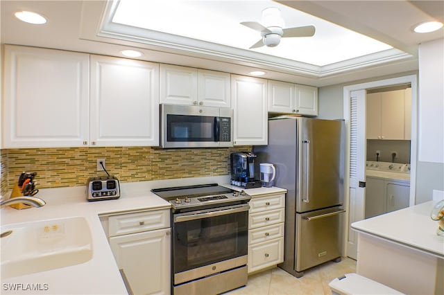 kitchen with sink, light tile patterned floors, separate washer and dryer, white cabinetry, and stainless steel appliances