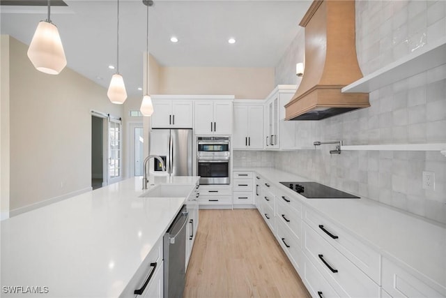 kitchen featuring white cabinetry, stainless steel appliances, tasteful backsplash, a barn door, and custom range hood