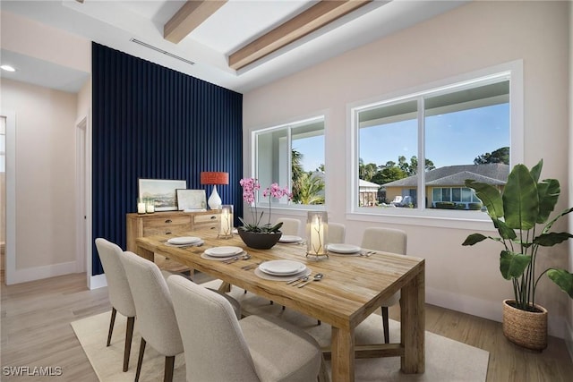 dining space with beamed ceiling and light hardwood / wood-style flooring