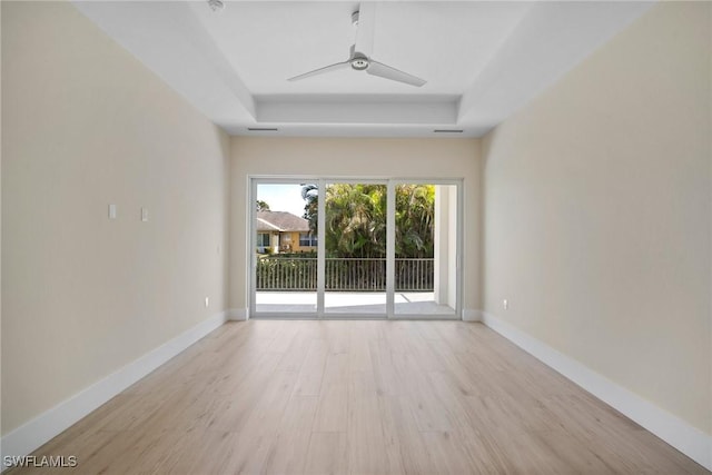 unfurnished room with light hardwood / wood-style floors, a raised ceiling, and ceiling fan