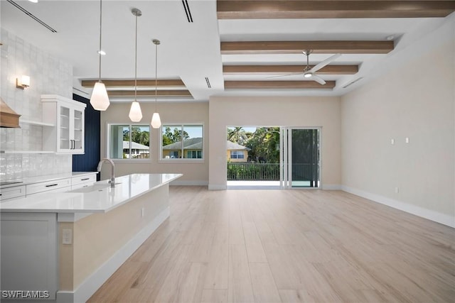 kitchen with decorative backsplash, ceiling fan, light hardwood / wood-style flooring, white cabinetry, and hanging light fixtures