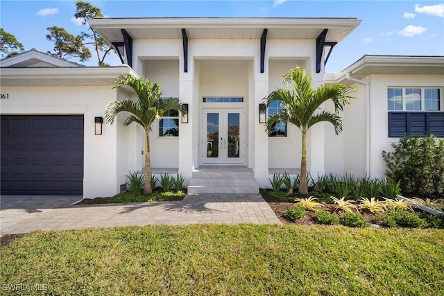 doorway to property featuring a garage, a yard, and french doors