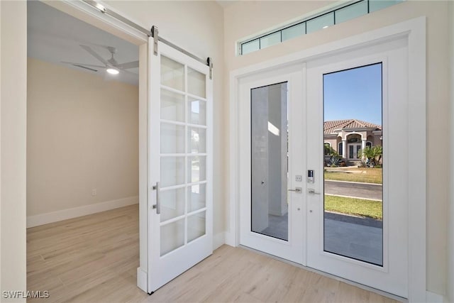 entryway with french doors, a barn door, light hardwood / wood-style flooring, and ceiling fan