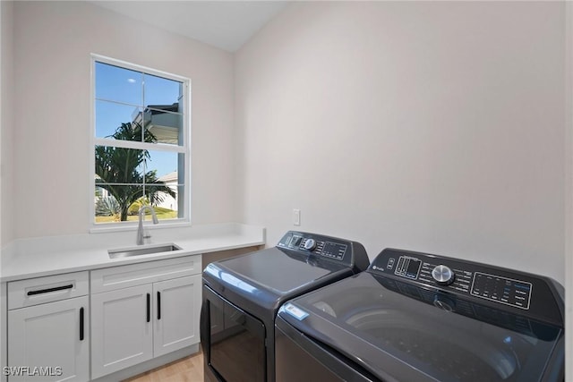 washroom with cabinets, separate washer and dryer, sink, and light hardwood / wood-style flooring