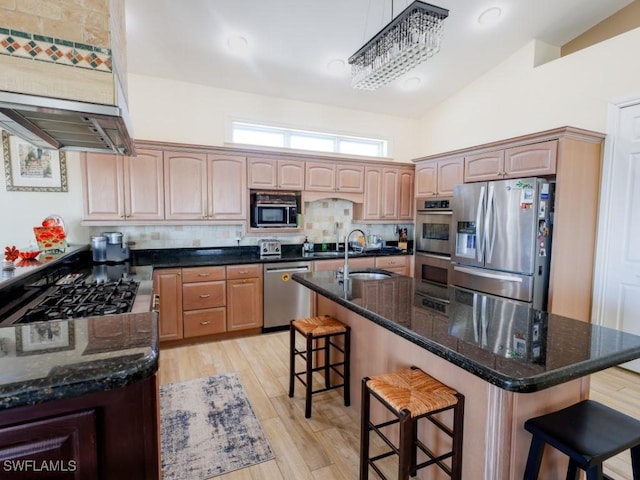 kitchen featuring a breakfast bar, sink, appliances with stainless steel finishes, and an island with sink