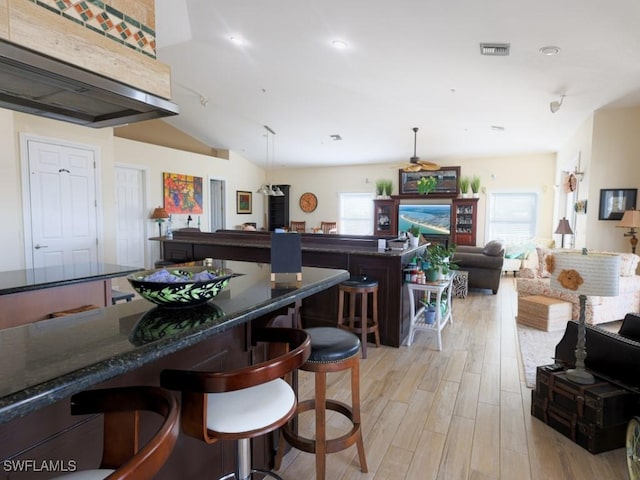 kitchen featuring pendant lighting, a kitchen breakfast bar, light wood-type flooring, and vaulted ceiling