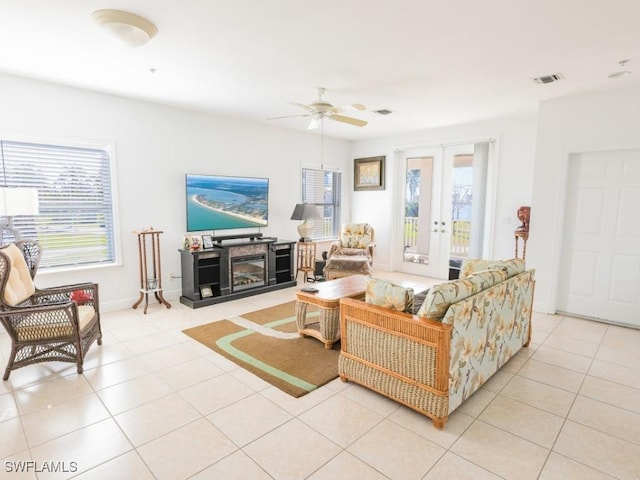 tiled living room with ceiling fan and french doors