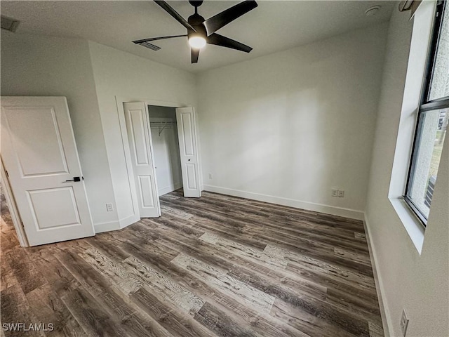 unfurnished bedroom with ceiling fan, a closet, and dark wood-type flooring