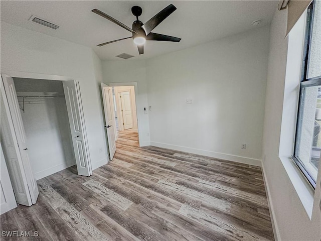 unfurnished bedroom with ceiling fan, a closet, and hardwood / wood-style flooring