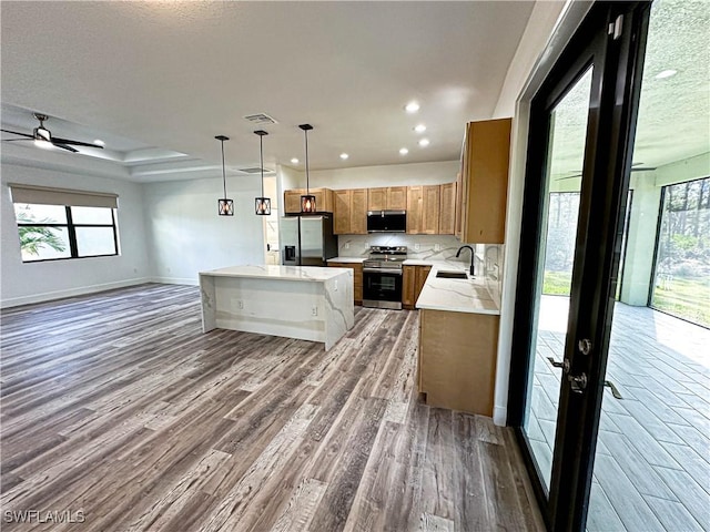 kitchen featuring appliances with stainless steel finishes, a kitchen island, plenty of natural light, and pendant lighting