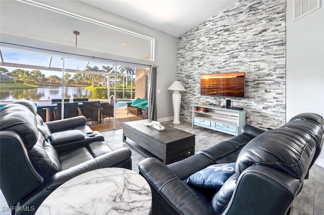 living room with a water view, light wood-type flooring, and vaulted ceiling