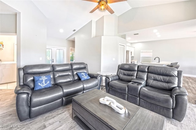 living room with ceiling fan, lofted ceiling, washer / clothes dryer, and light hardwood / wood-style flooring